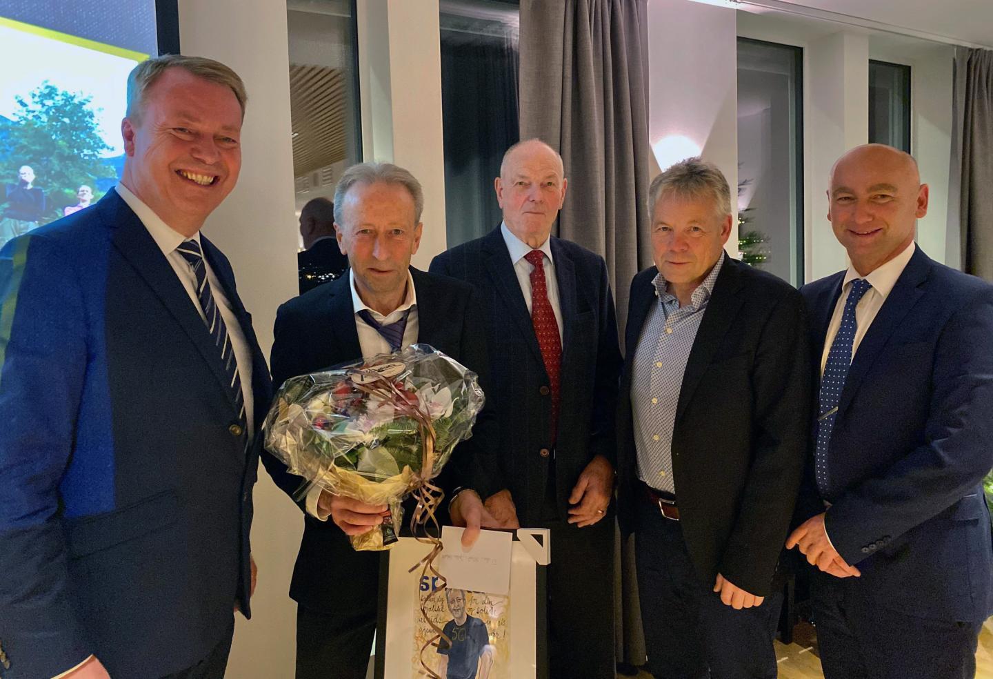Gruppe på 5 ansatte, den ene har fått en blomsterbukett